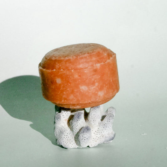 Cylindrical orange object on a white base with a light green background