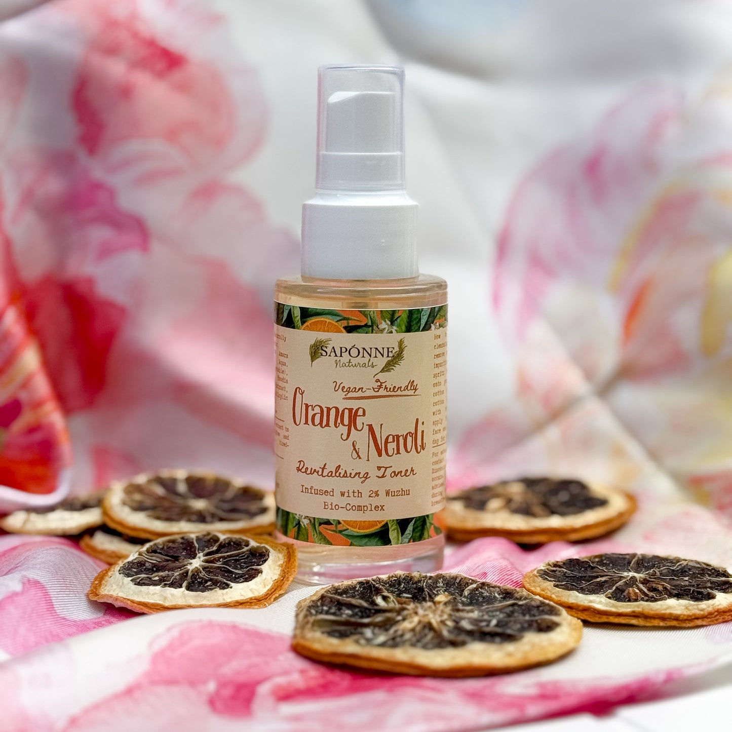 Bottle of Saponne Orange & Neroli toner with dried orange slices on a floral background