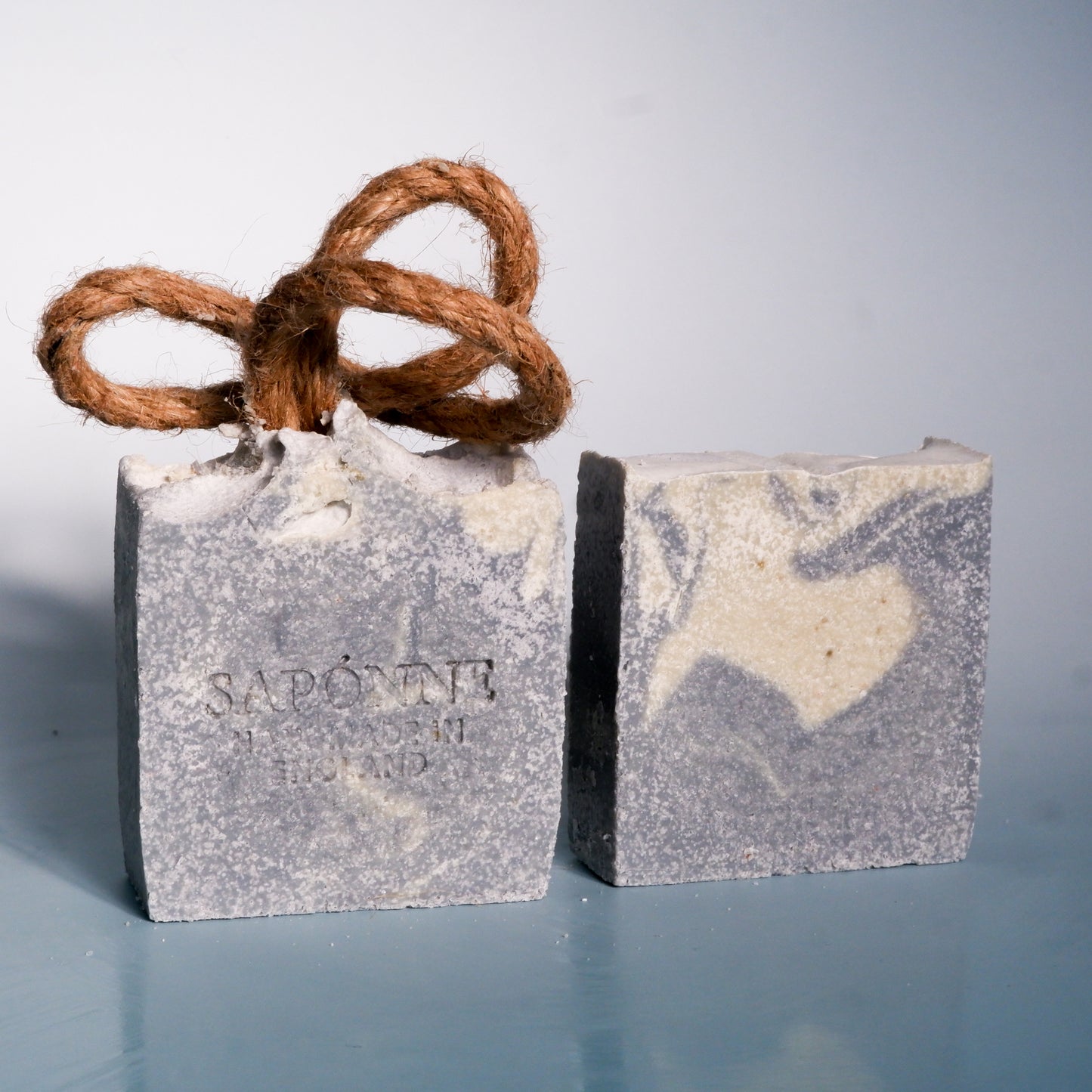 Two soap bars with a rope on a gray background