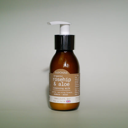 Brown bottle with a white pump labeled 'Saponne organic rosehip & aloe cleansing milk' on a light gray background
