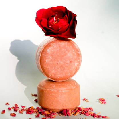 Two stacked shampoo bars with a red rose on top against a white background