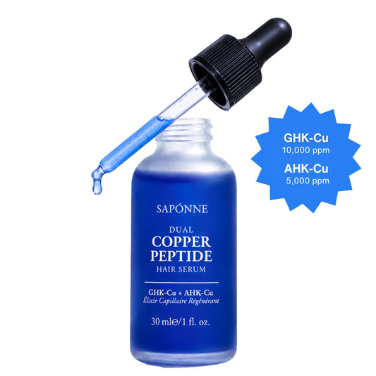 Sapónne Dual Copper Peptide Hair Serum in a 30 ml blue glass dropper bottle with a black cap, shown with the dropper tipped over the bottle and a blue starburst callout listing GHK-Cu and AHK-Cu concentrations.