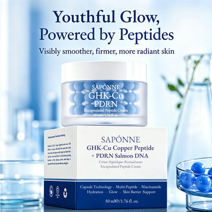 Sapónne GHK-Cu + PDRN Encapsulated Peptide Cream shown in a clear jar with blue gel spheres, placed in front of its white and navy box. The scene is a styled studio setup with a soft blue background, decorative glassware, and text reading 'Youthful Glow, Powered by Peptides.