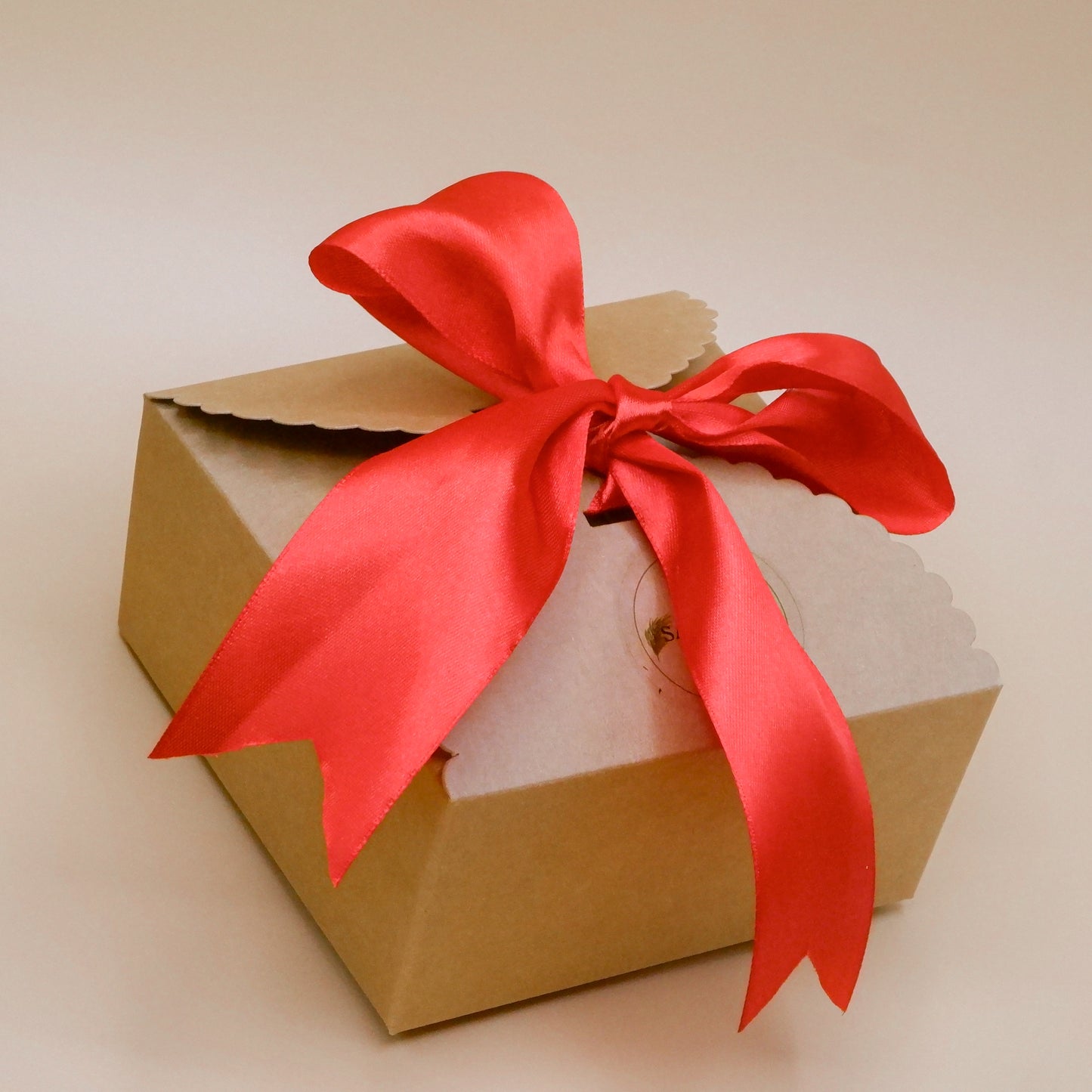 Brown gift box with a red ribbon on a beige background