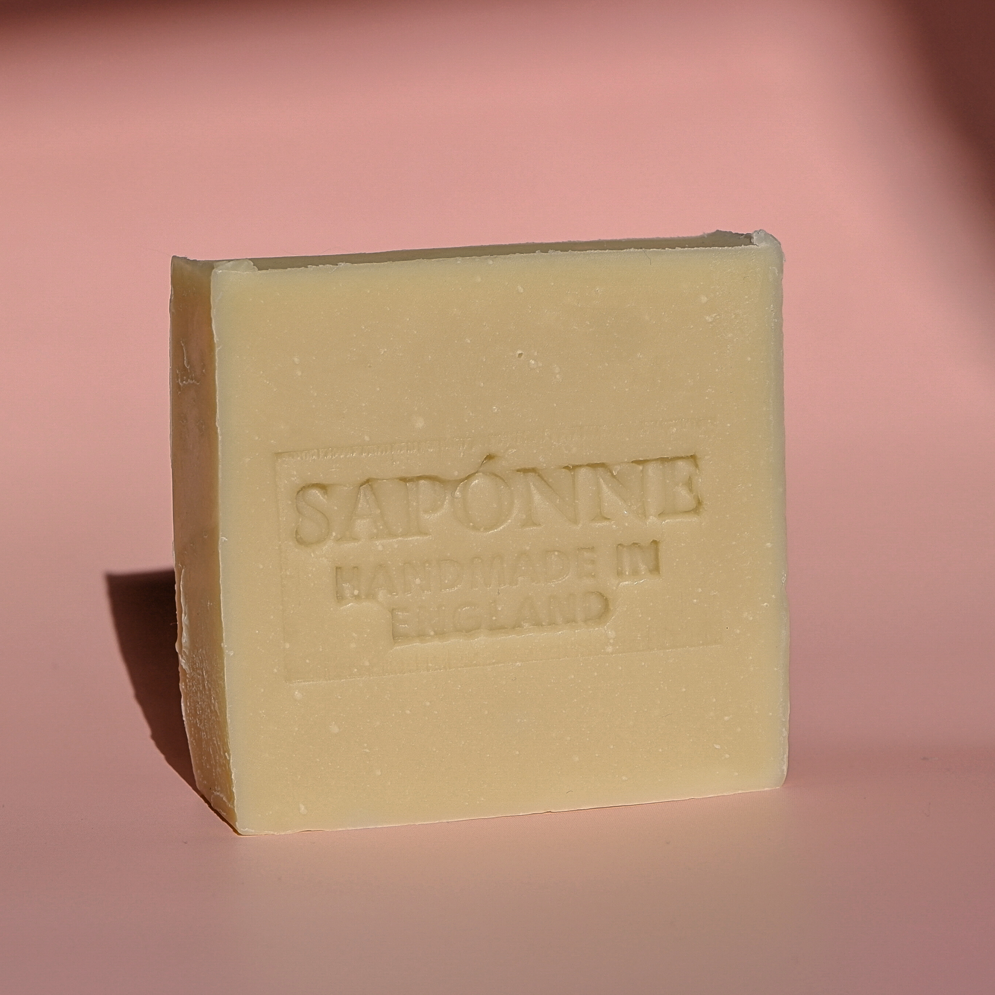 Bar of soap with 'Saponine' branding on a pink background
